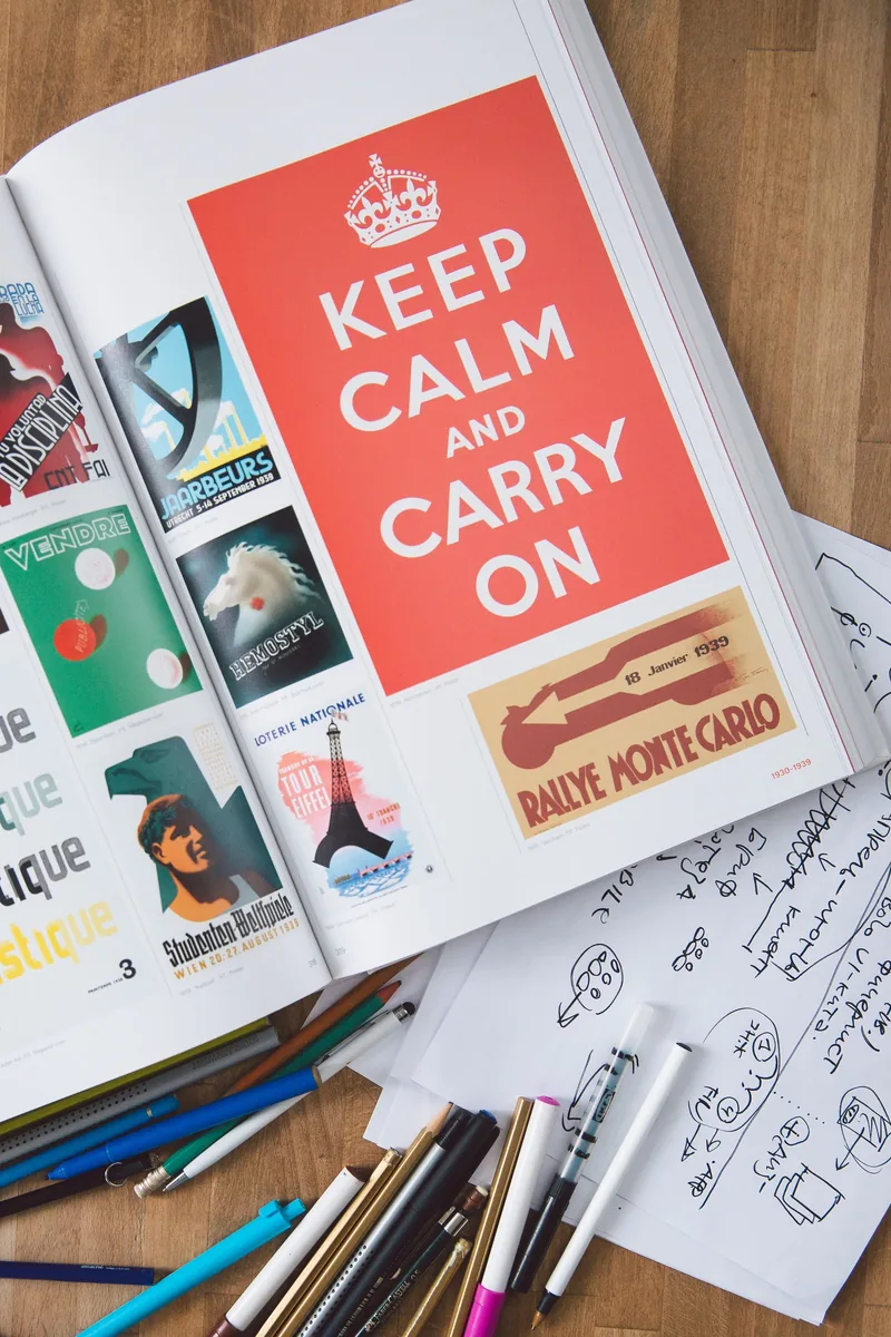 An open design book, papers and drawing tools on a worktable