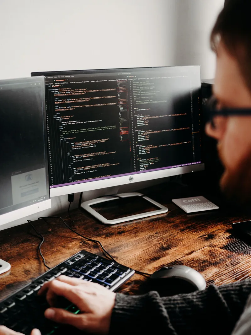 A developer working with code on two monitors